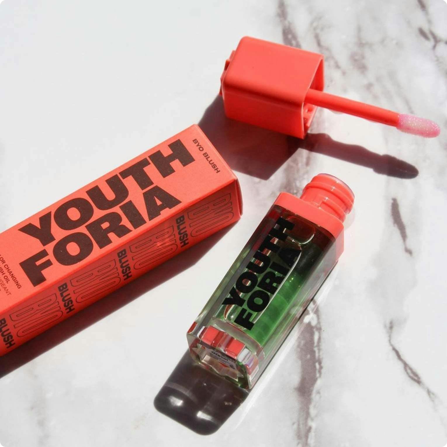 Bright orange product shot of Youthforia on a white marble table