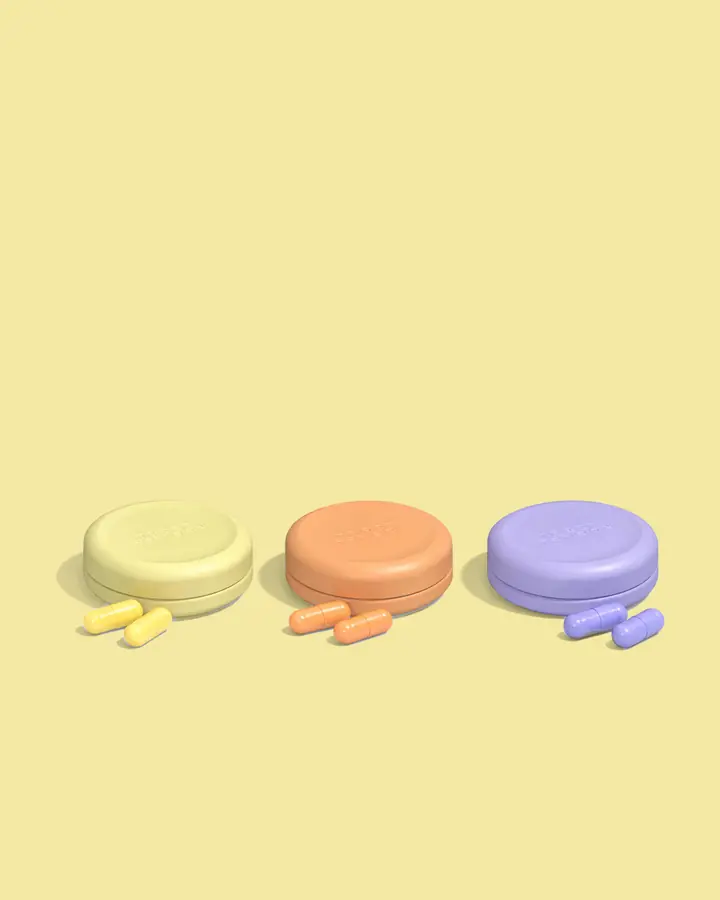 First Person Sunbeam, Golden Hour, and Moonlight tins lined up with their capsules on a pale yellow backdrop