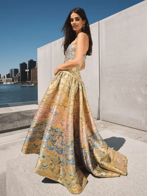 A model in a Mestiza jacquard ball gown on a stone terrace, with the New York skyline behind her