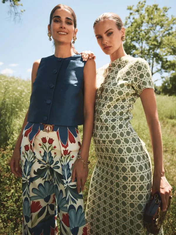 2 models in Mestiza printed looks, a floral wide-leg pant and a lattice-print dress, in a summer field