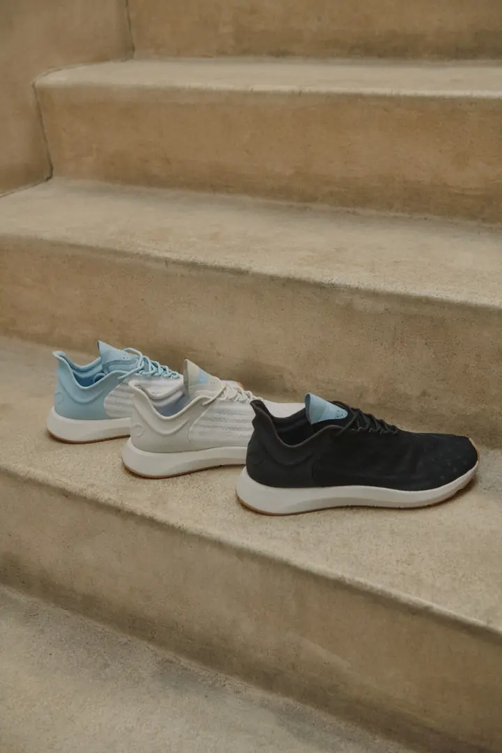 3 Saysh sneakers in blue, white, and black lined up on worn stone steps