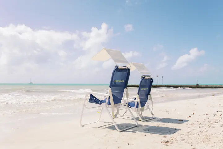 2 navy Sunflow chairs with sun shades at the water's edge