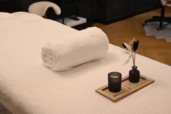 Treatment table with a rolled towel and a candle tray in a calm, softly lit spa room