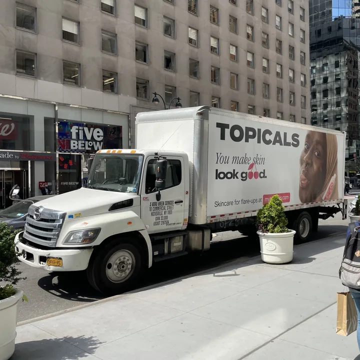 Topicals truck wrapped with its "You make skin look good" ad, parked on a Midtown Manhattan street