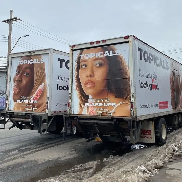 Two Topicals trucks seen from behind, their rear doors wrapped with "Skincare for flare-ups" ads