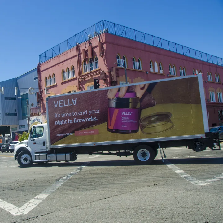 Vella truck wrapped with its Women’s Pleasure Serum ad, crossing an intersection under the Venice sign in Los Angeles